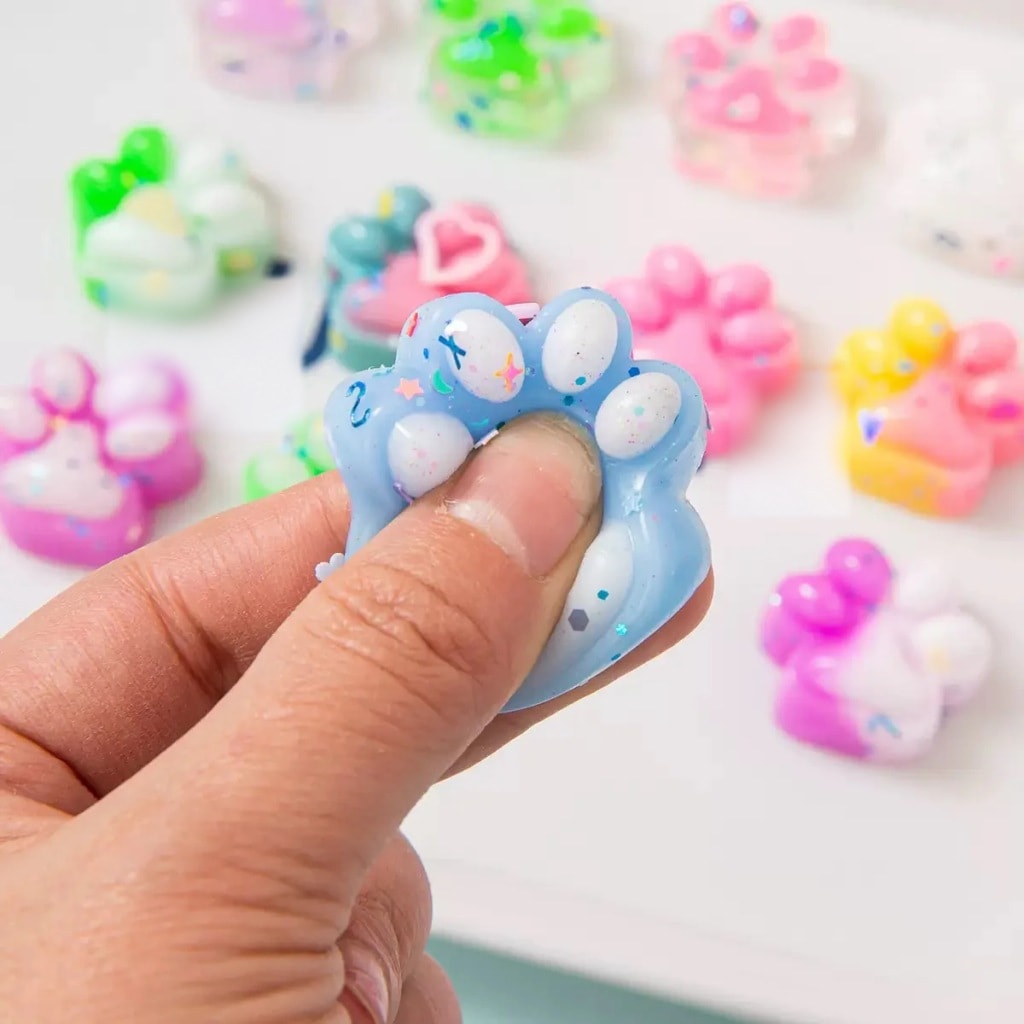 Dłoń ściska niebieską kocią łapkę squishy